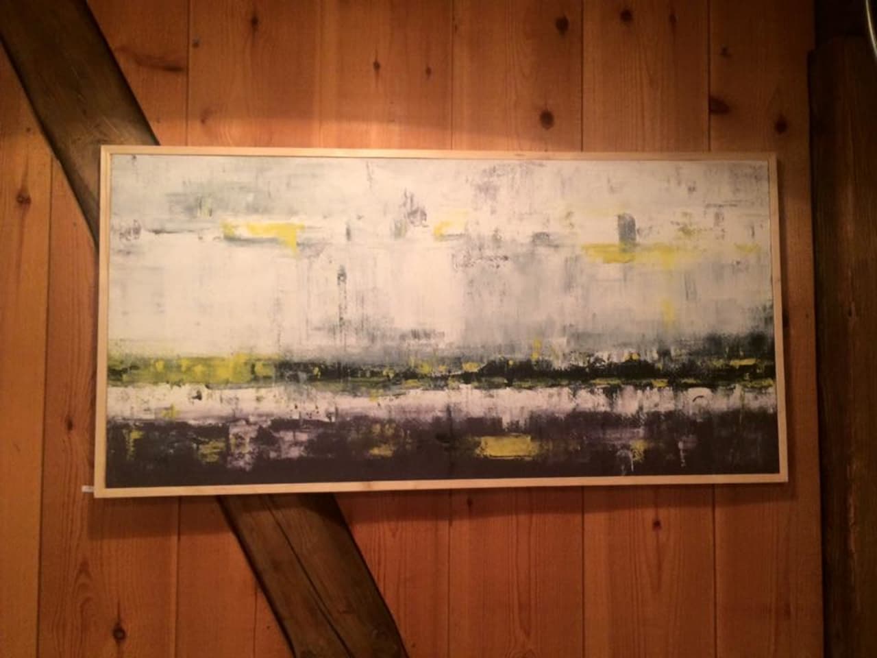 Artwork displayed on a wood-paneled wall inside Langabúð Cultural Center