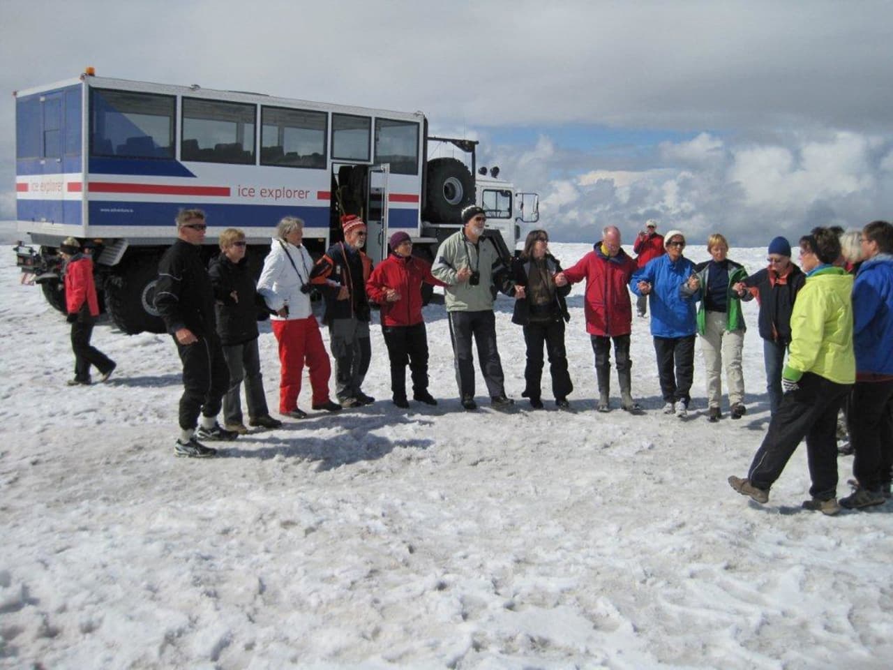 A glacier truck and guided group on the snowy surface of Langjökull in Iceland.