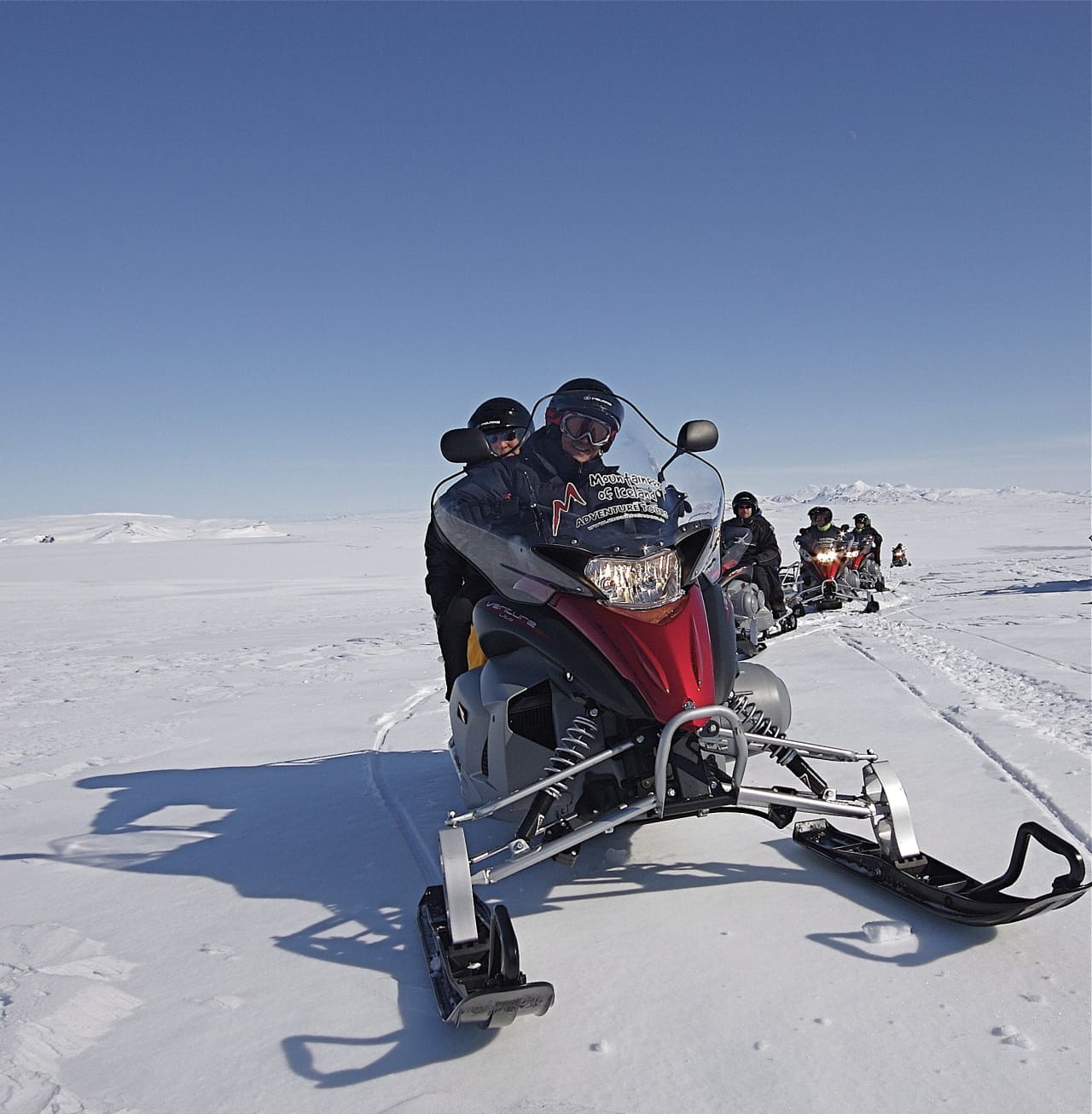 A line of guided snowmobiles crossing the snowy surface of Langjökull glacier.