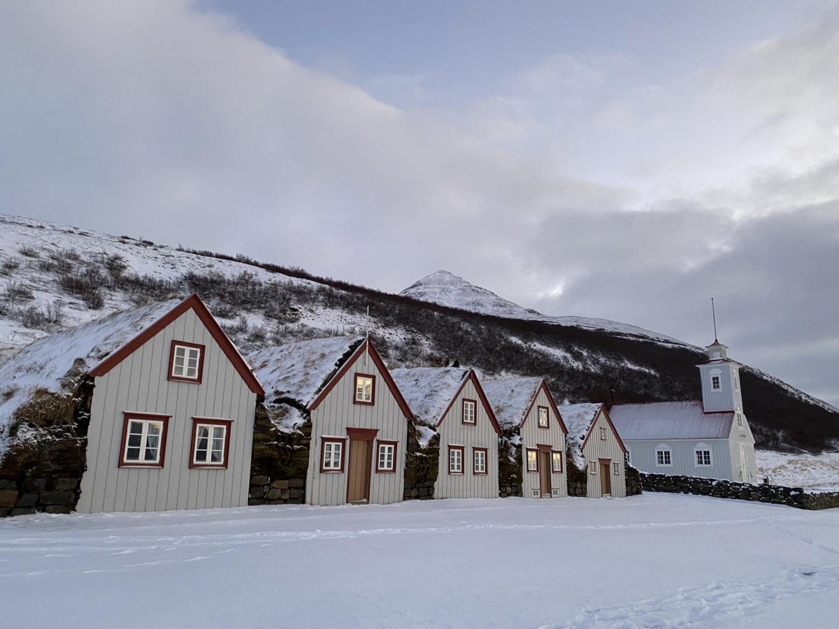 Laufás turf farm and church in winter snow below the Eyjafjörður hillside.