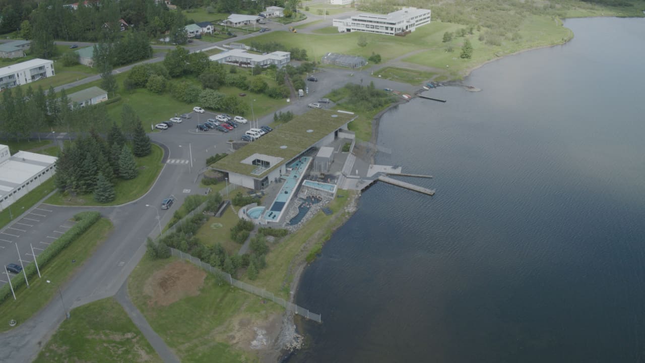 Laugarvatn Fontana, nearby roads, parking areas, and the edge of Lake Laugarvatn seen from above.