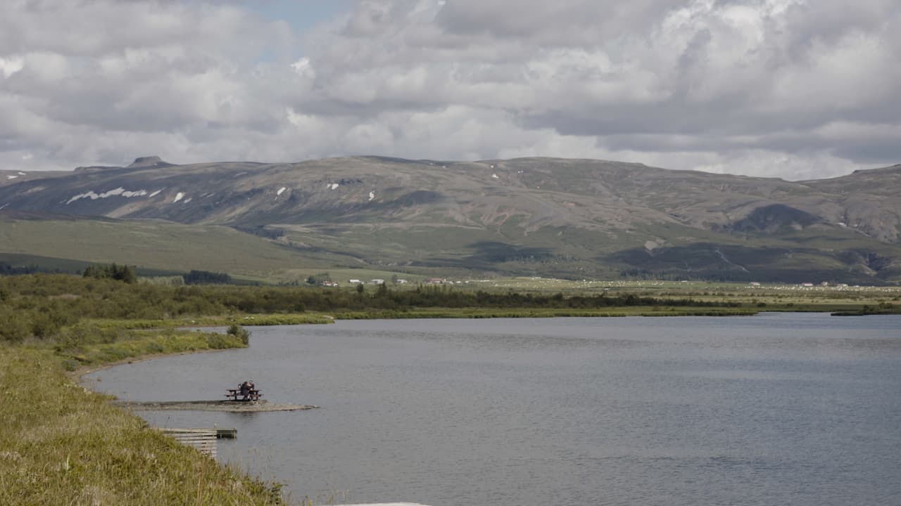 Lake Laugarvatn with low mountains and cloudy South Iceland sky beyond the shore.