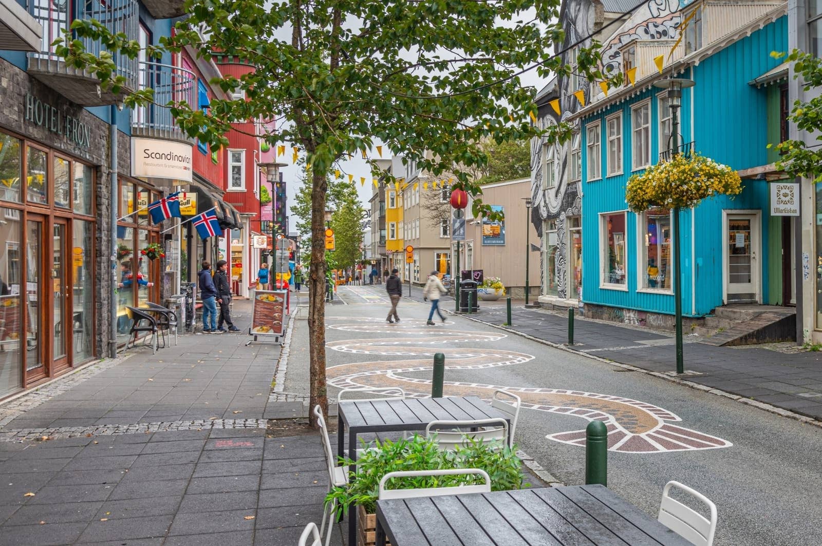 People walking past colorful buildings and cafe seating on Laugavegur in Reykjavík.