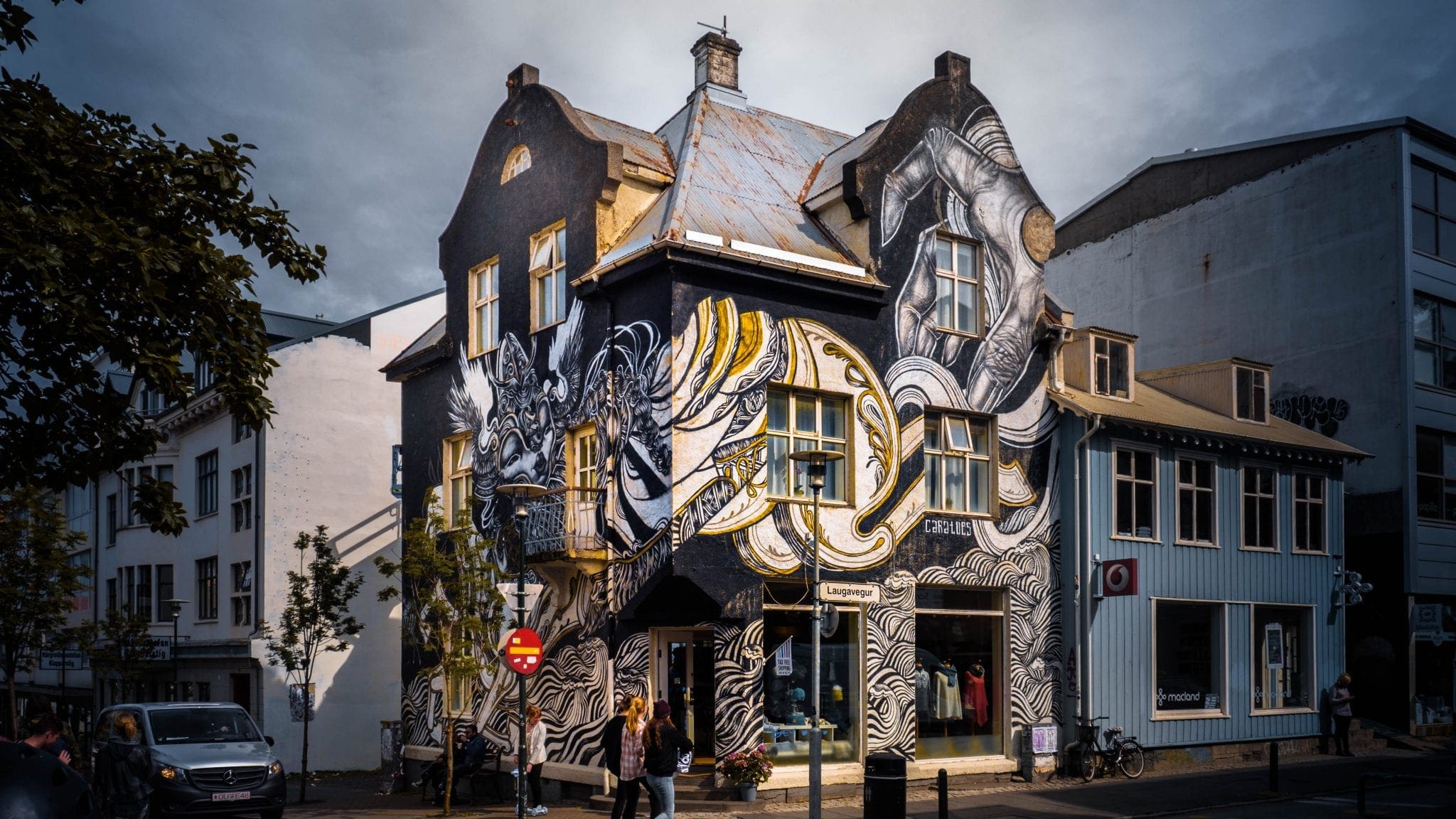Large black and white mural on a building beside a Laugavegur street sign in Reykjavík.