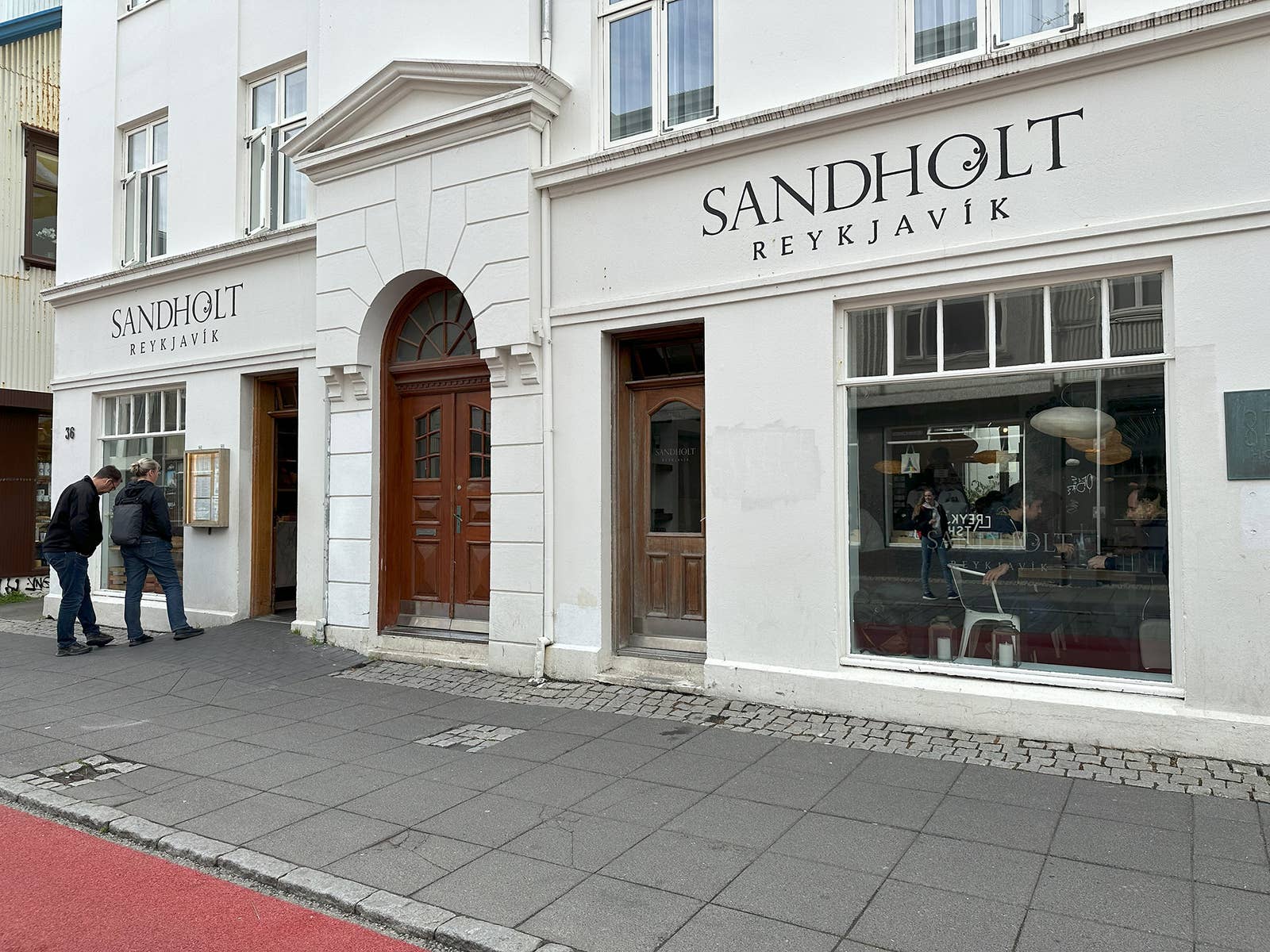White storefront facade on Laugavegur in Reykjavík with pedestrians on the sidewalk.