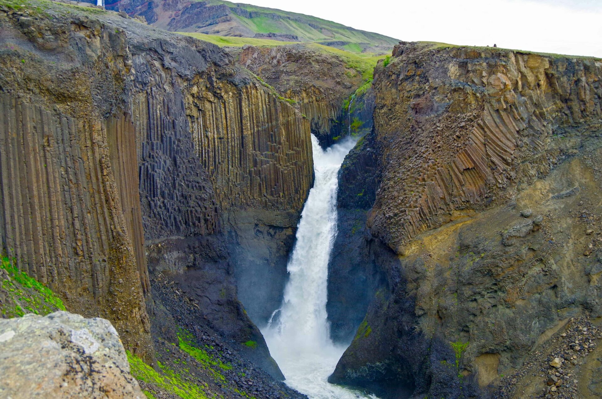 Litlanesfoss dropping between tall basalt columns in a narrow East Iceland gorge.