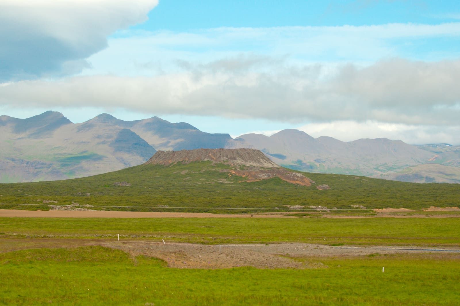 Ljósufjöll mountains rising behind Eldborg crater and green West Iceland lowlands.