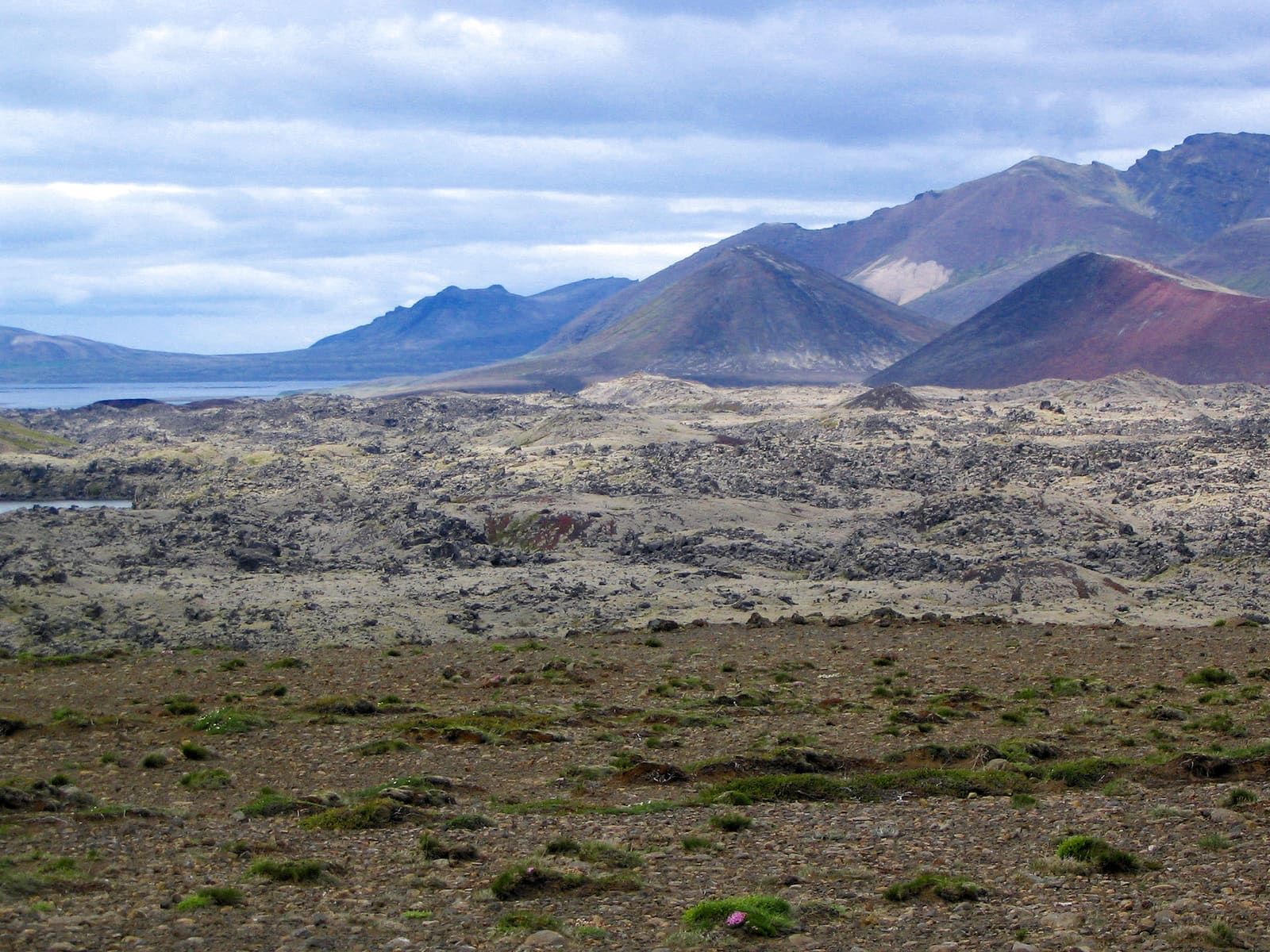 Rough lava field and reddish volcanic hills in the Ljósufjöll system on Snæfellsnes.