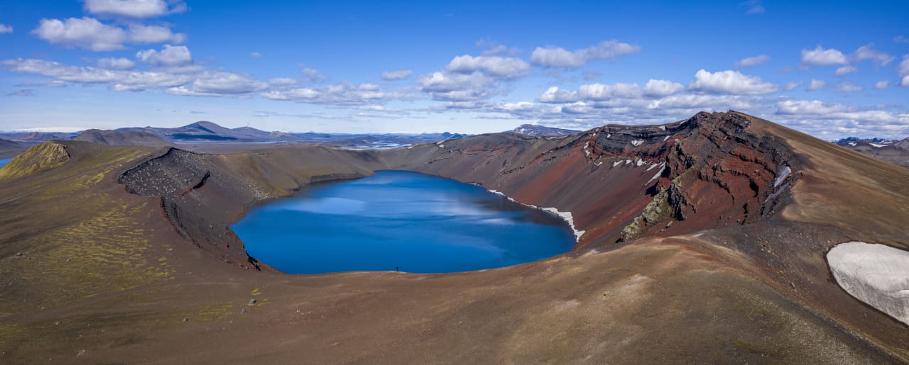Blue Ljótipollur crater lake surrounded by red and brown volcanic slopes in the South Highlands.