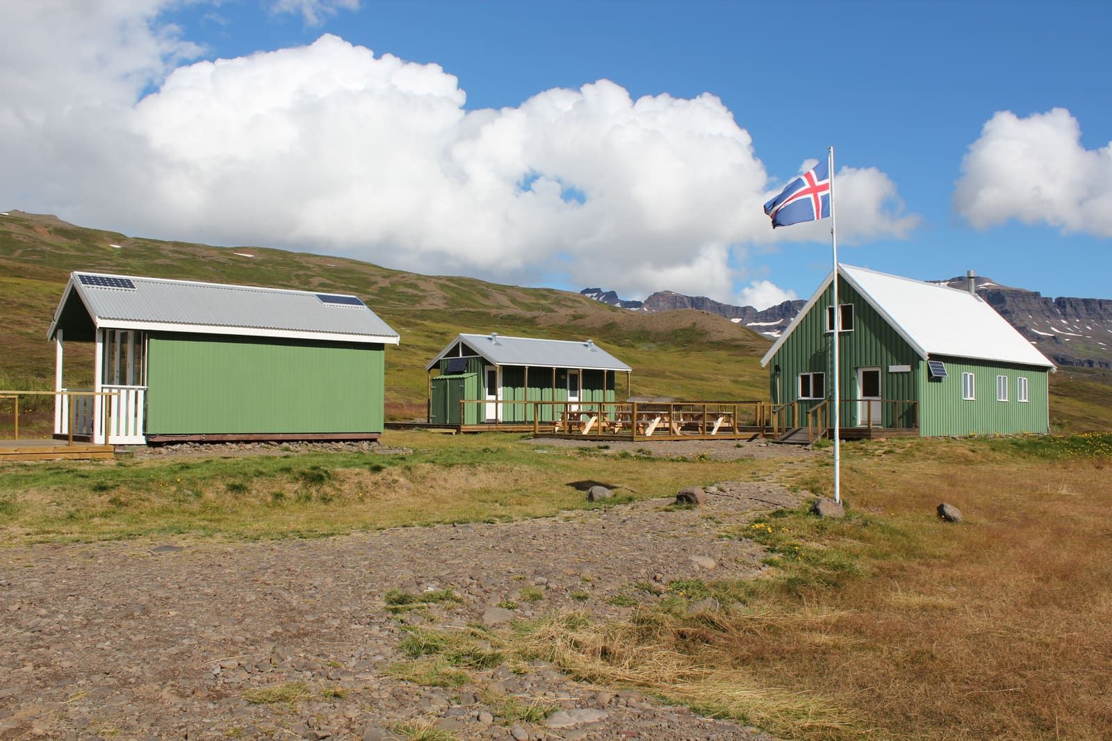 Green huts at Klyppstaður in Loðmundarfjörður with mountains behind.
