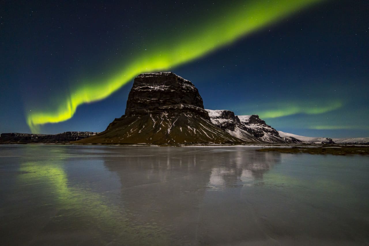 Northern lights above the snowy silhouette of Lómagnúpur in South Iceland.