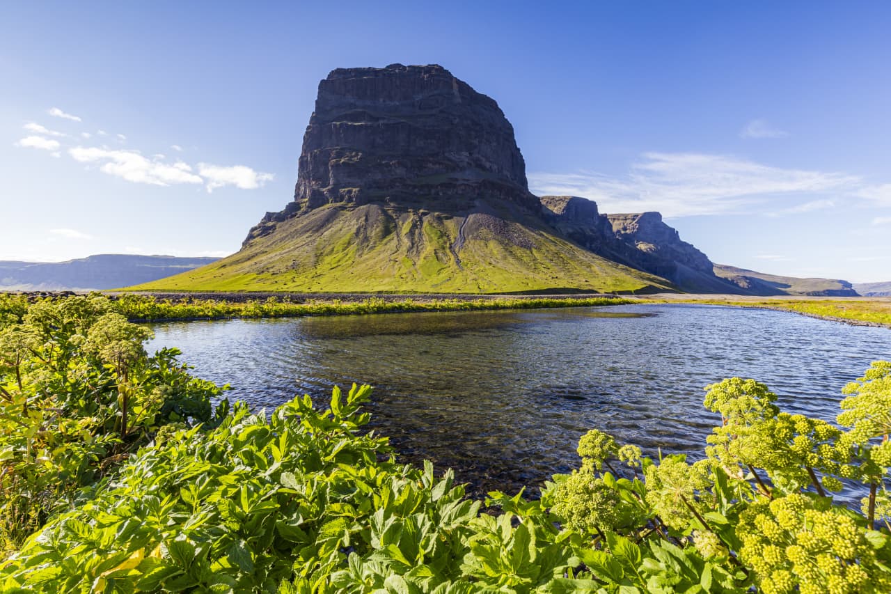 Lómagnúpur rising above a river and green foreground on the South Coast.