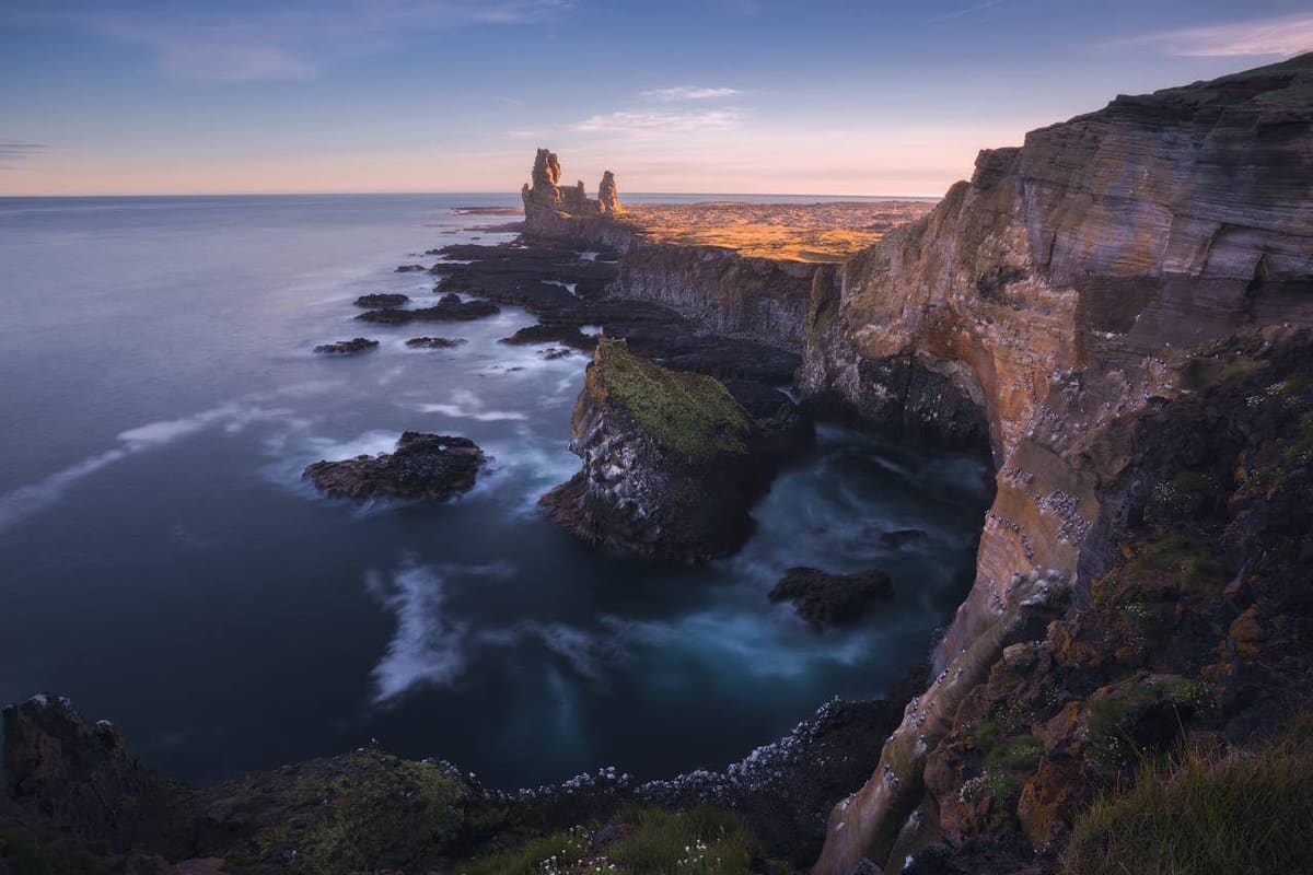 Lóndrangar stacks silhouetted beyond the dark Snæfellsnes coast at dusk.