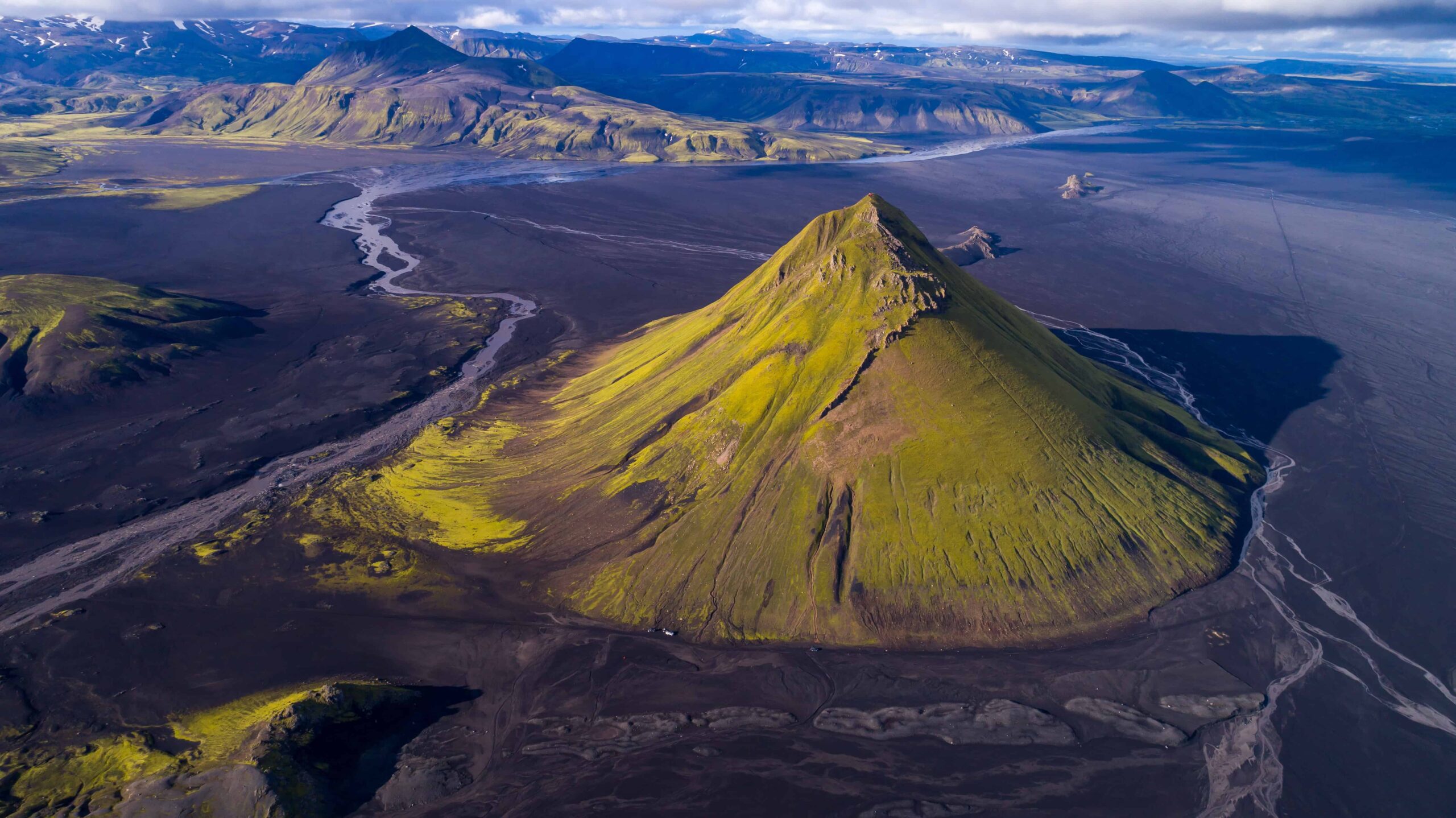 Aerial view of Mælifell rising green from the black Mælifellssandur plain.
