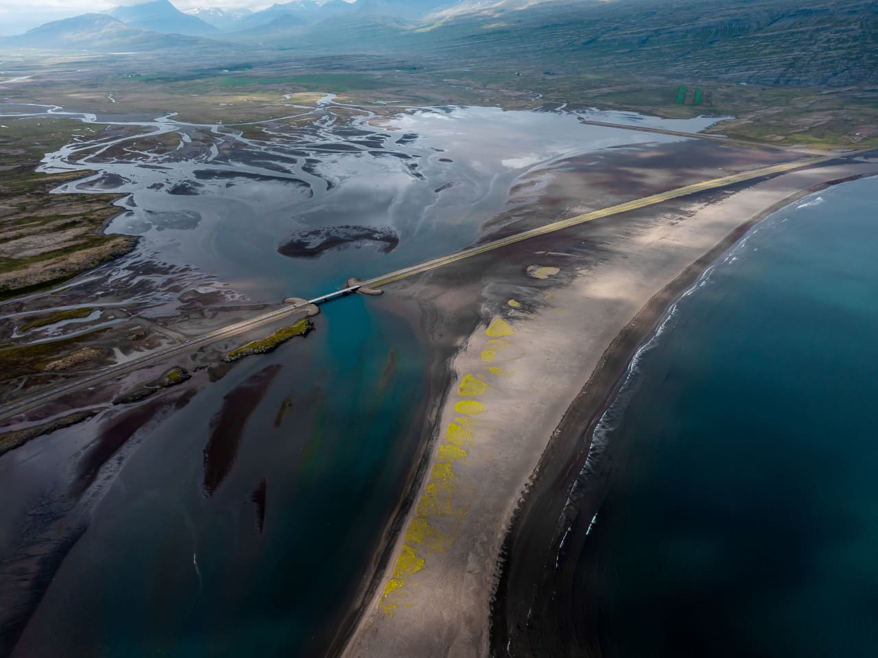 Aerial view of Meleyri Beach, the lagoon, and the road across the black-sand spit by Breiðdalsvík.