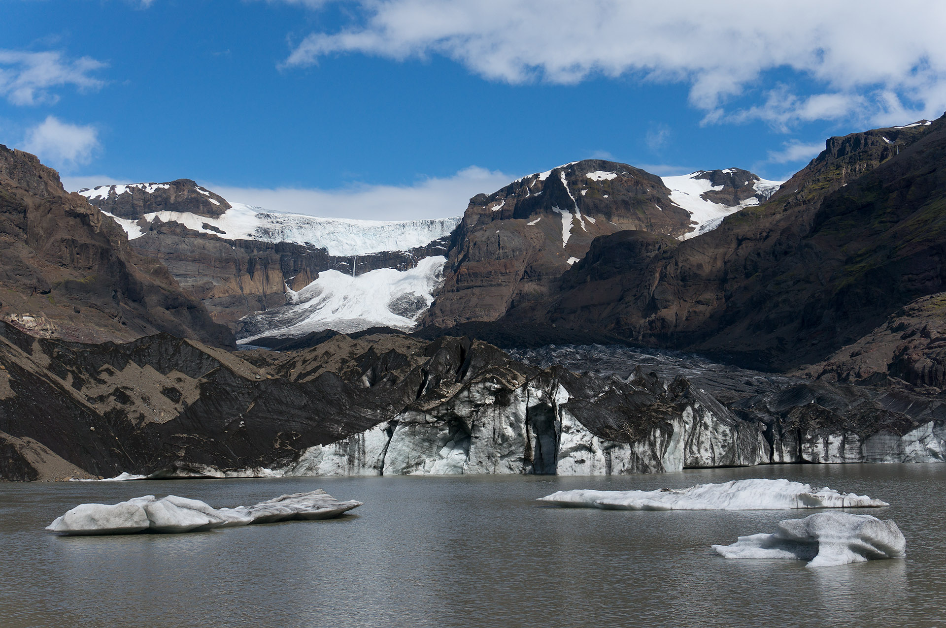 Morsárfoss seen in the distance above Morsárjökull glacier and a glacial lagoon in Vatnajökull National Park.