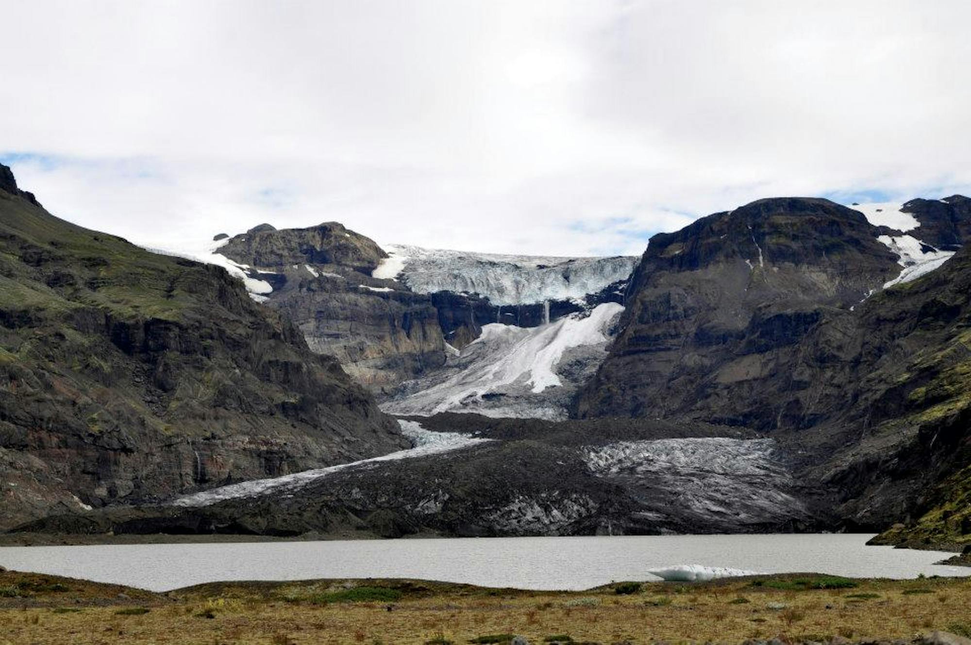 Morsárjökull above a glacial lake, with dark cliffs and ice below the Vatnajökull ice cap.