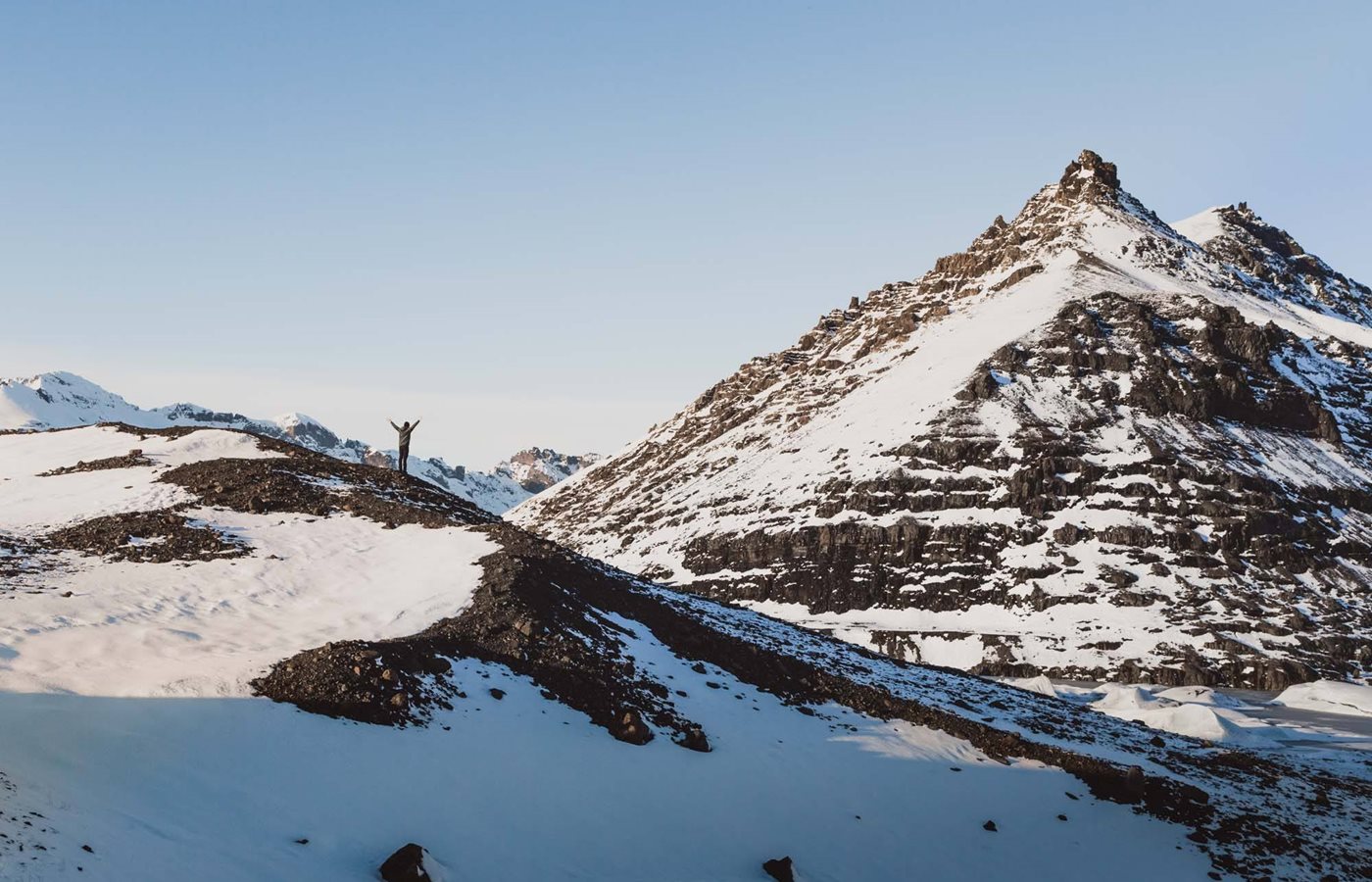 Small figure standing on snowy volcanic ridges near Mýrdalsjökull in South Iceland.