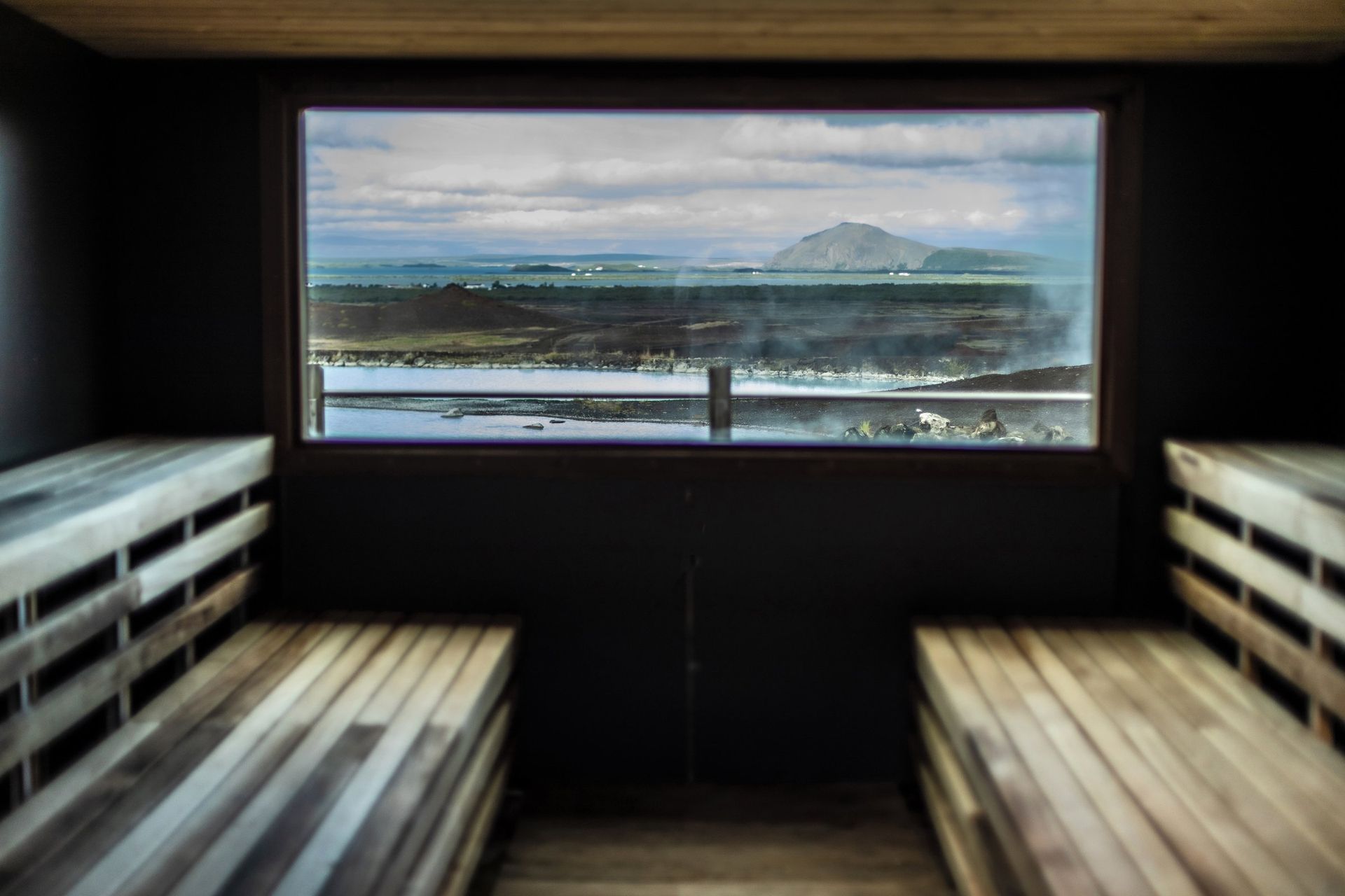 Steam-bath room at Earth Lagoon Mývatn looking out toward Lake Mývatn and volcanic hills.