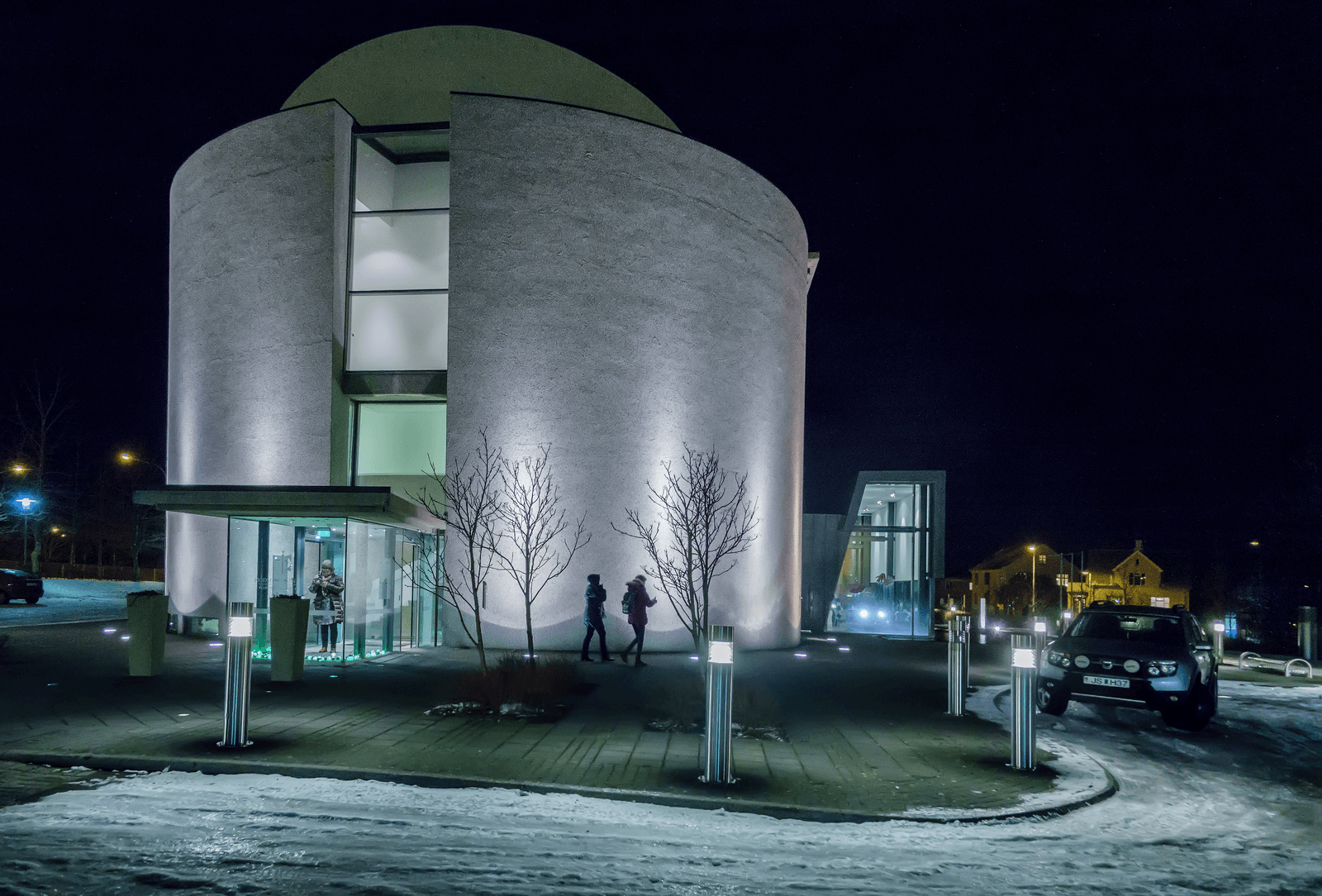 National Museum of Iceland entrance lit at night with snow along the Reykjavík pavement.