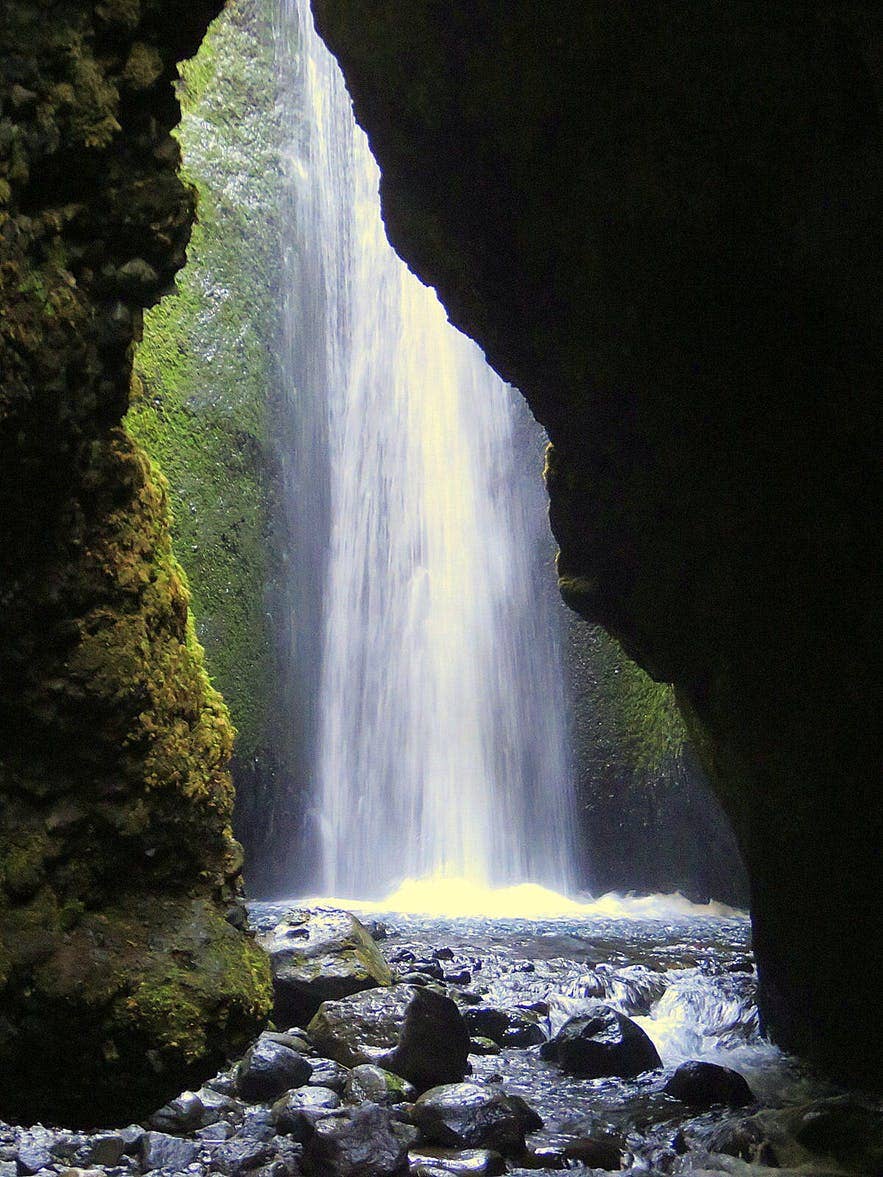 Waterfall dropping inside the dark, narrow Nauthúsagil ravine.