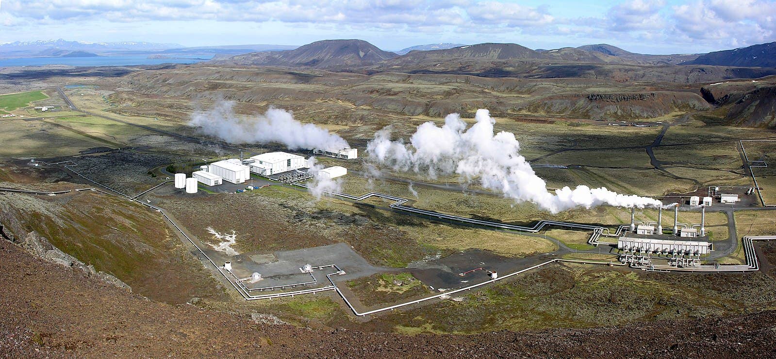 Wide view of Nesjavallavirkjun, geothermal steam pipes, Lake Þingvallavatn, and the surrounding volcanic slopes.
