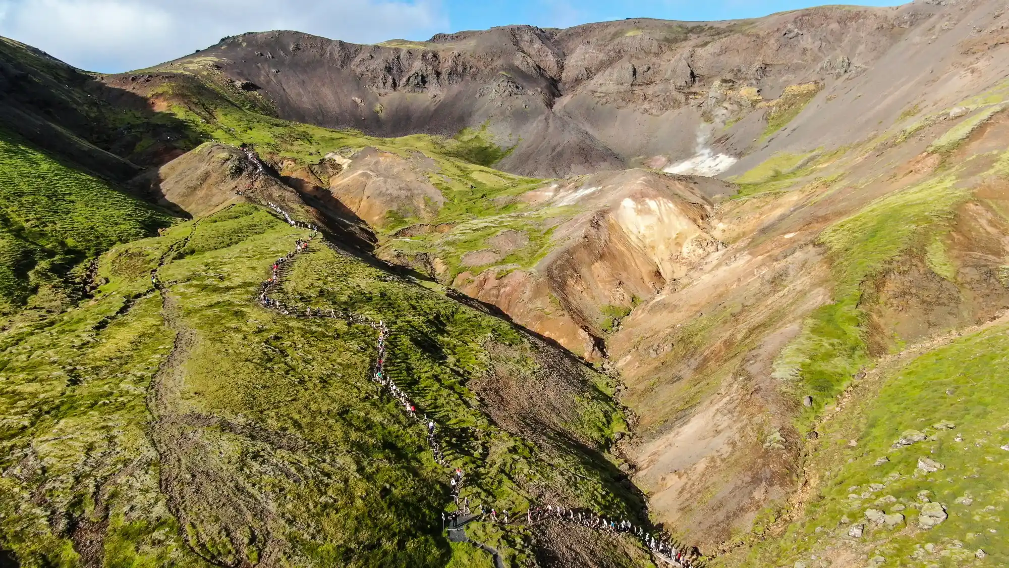 Hikers crossing colorful Hengill geothermal slopes near the Nesjavellir area.