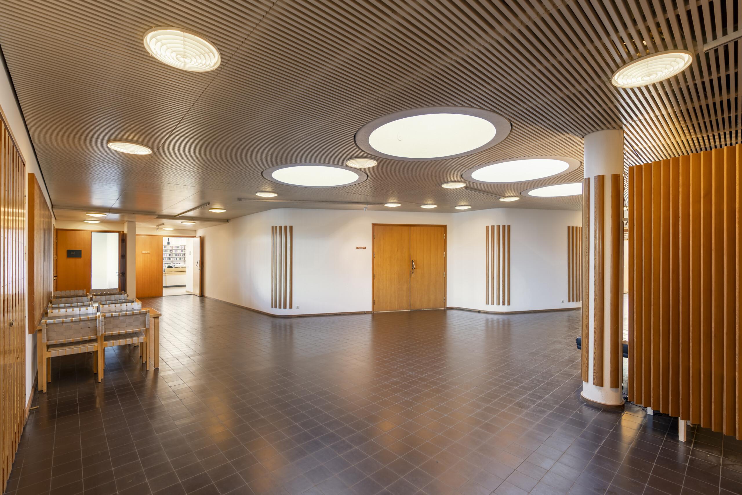 Wood-lined auditorium area inside the Nordic House with round ceiling lights and Aalto interior details.