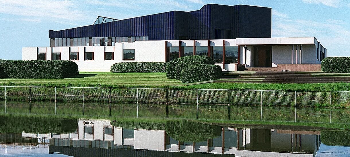 The Nordic House in Reykjavik seen from across the wetland with the blue roof and white facade.