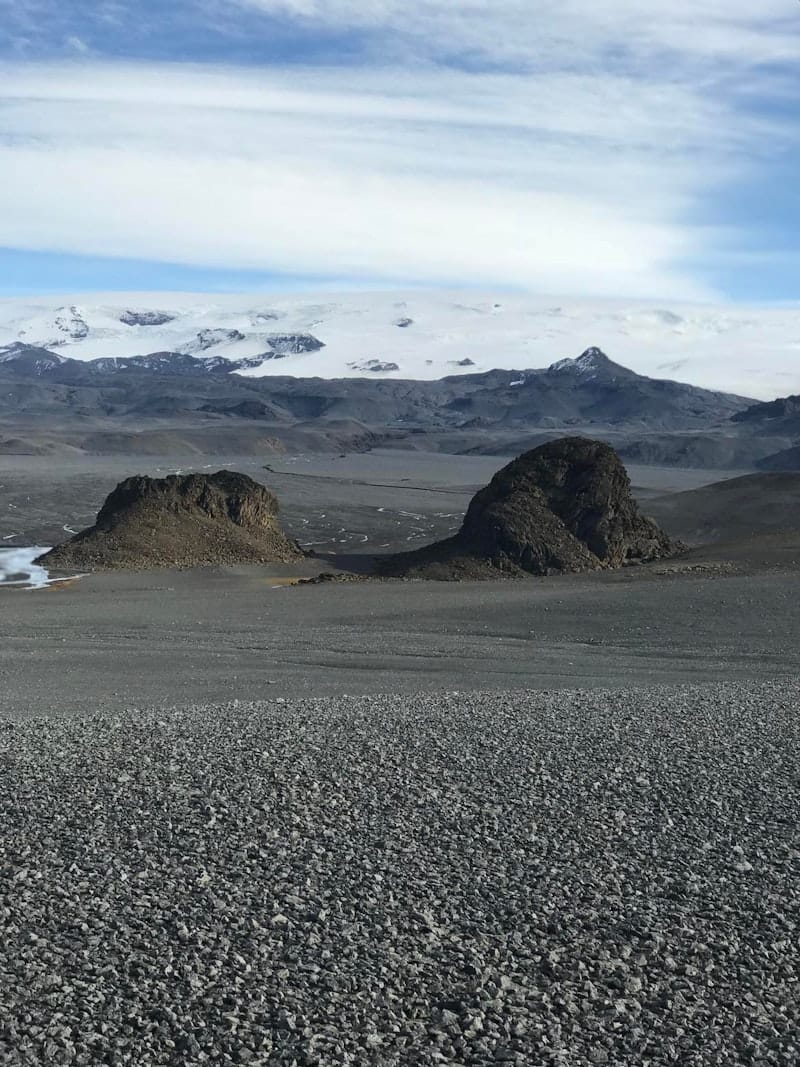 Dark Hníflar rock formations below a broad white glacier in the Nýidalur Highlands area.