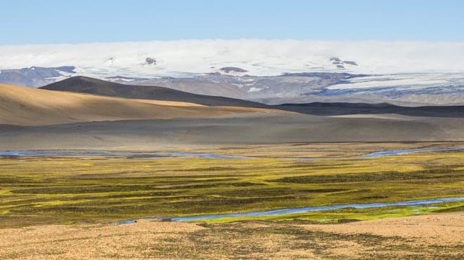 Vonarskarð and Bárðarbunga landscape with bright mossy ground, dark ridges, and distant glacier ice.