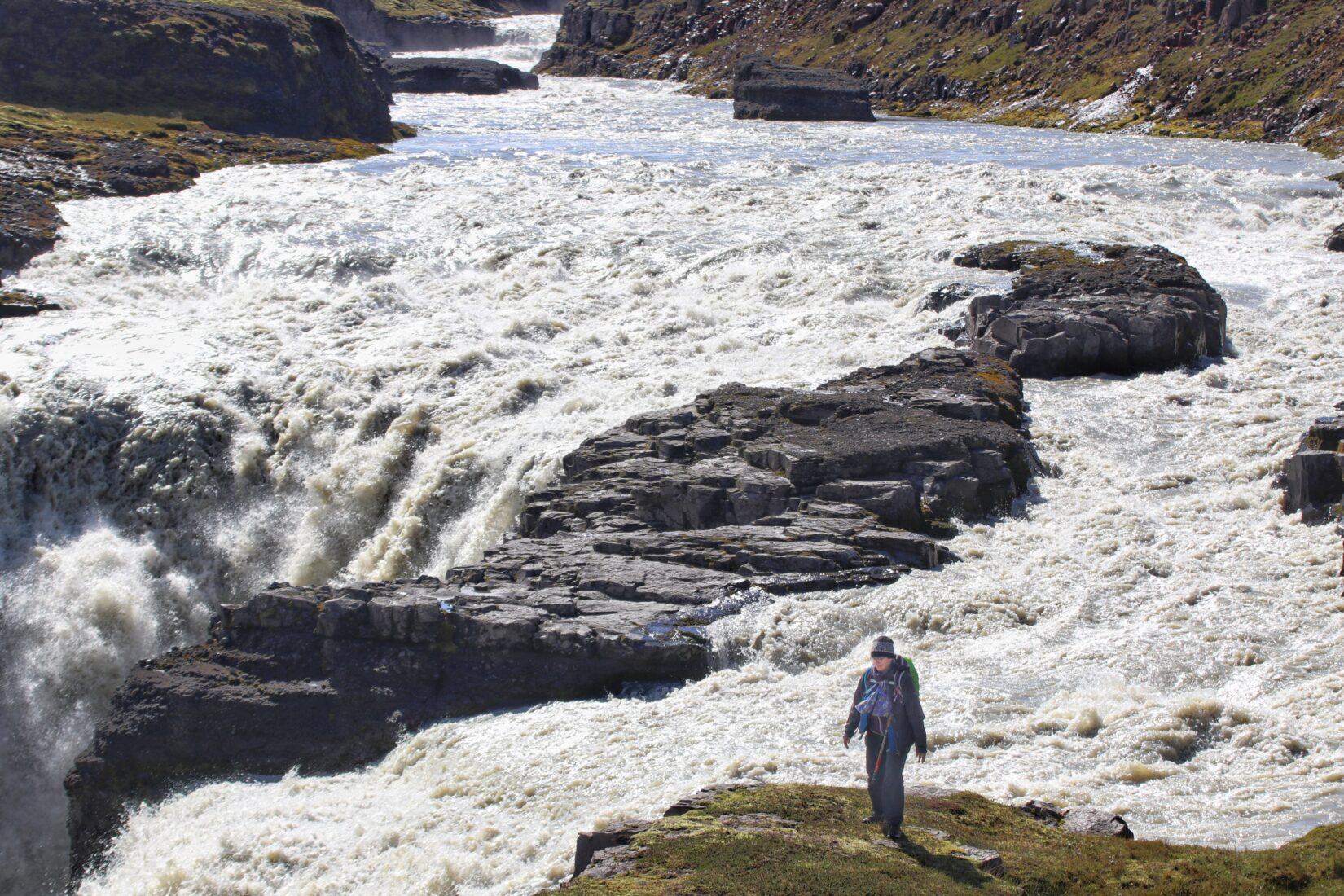 Hiker near a powerful waterfall on the Jökulsá in Fljótsdalur area connected with The Wilderness Center and the Waterfall Trail.