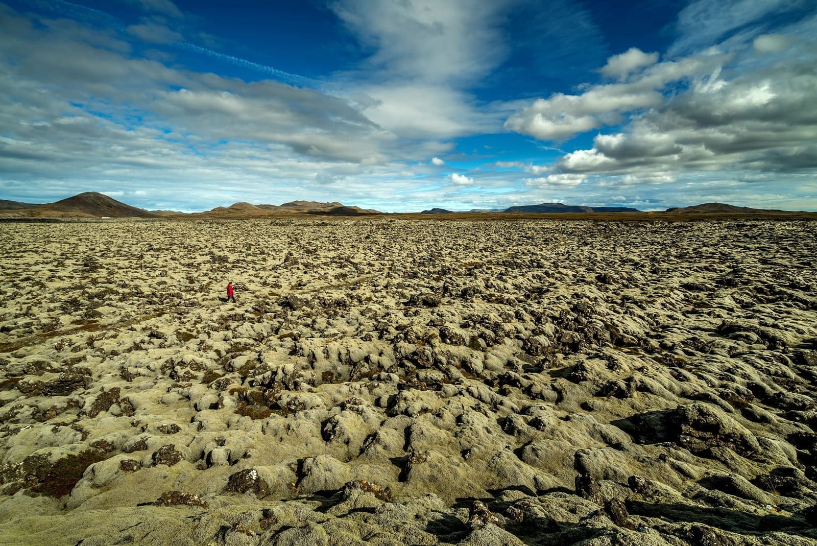 Wide view over moss-covered Ögmundarhraun lava field with low Reykjanes mountains beyond.