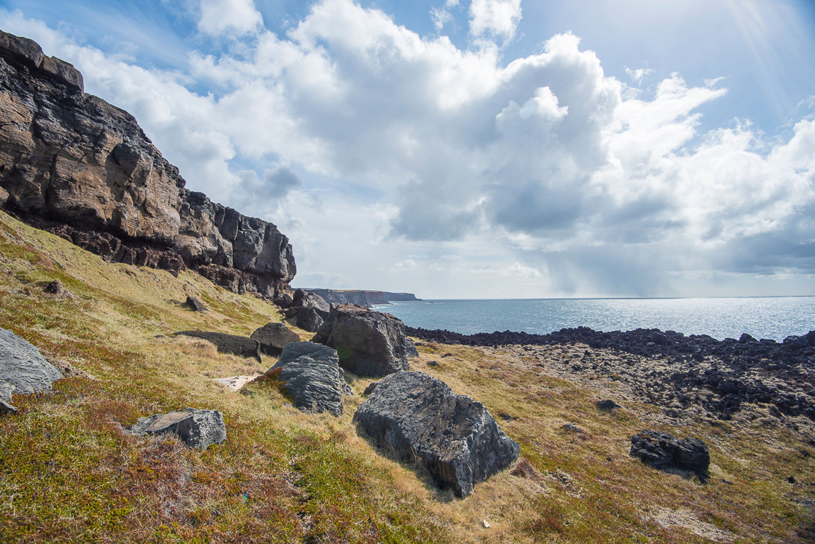 Rocky shoreline and dark lava near the coastal edge of Ögmundarhraun and Húshólmi.