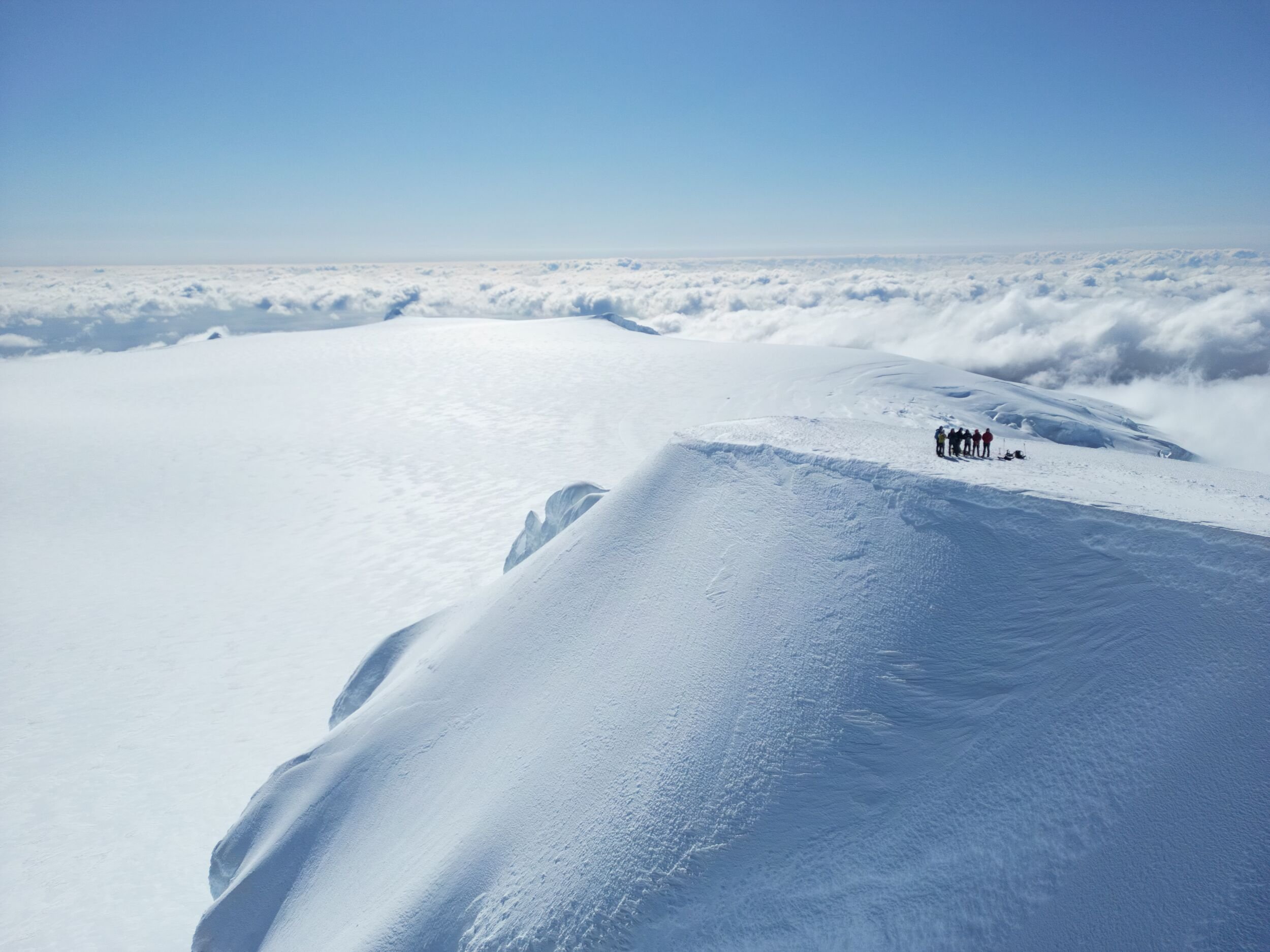 A small group standing on the snowy Öræfajökull ice cap above clouds in southeast Iceland.