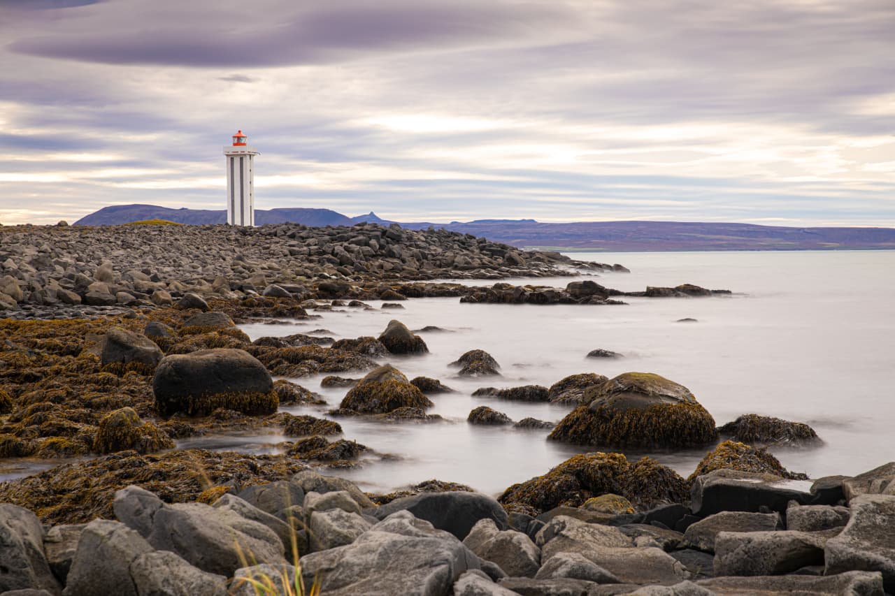 Kópasker lighthouse beside a rocky shore on Öxarfjörður bay.