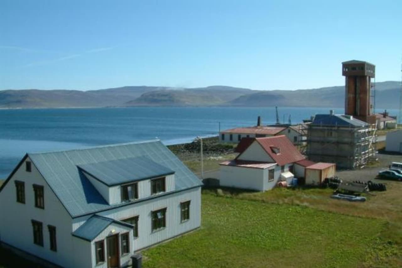 Harbor buildings and fjord water in Patreksfjörður with Westfjords hills across the bay.