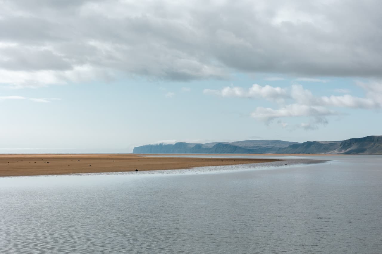 Calm water channels and red-gold sand at Rauðasandur Beach under low Westfjords cloud.