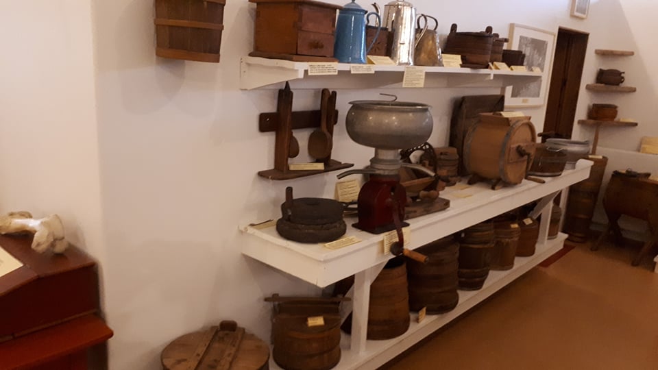 Farmhouse objects, barrels, and household tools displayed on shelves inside Reykir Regional Museum.