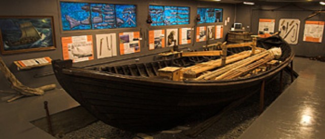 Wide view of the Ófeigur boat and exhibit panels inside Reykir Regional Museum.