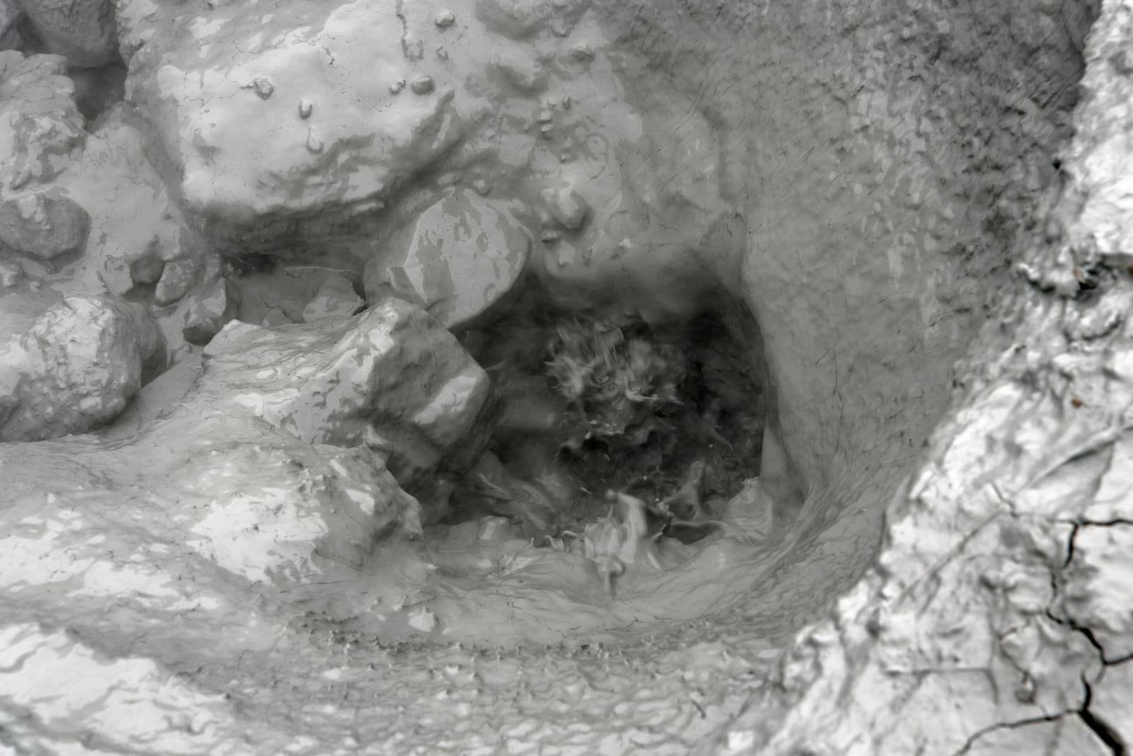 Close view of steaming grey geothermal mud and mineral ground in Reykjadalur.
