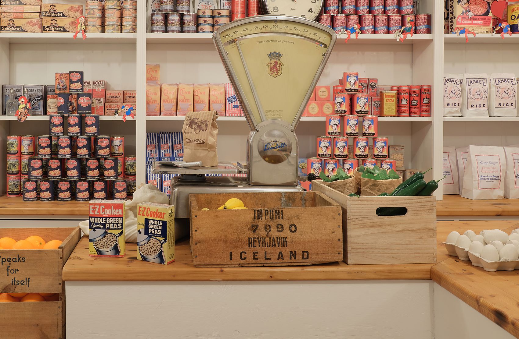 Historic shop display with tins, shelves, and a scale inside the Aðalstræti exhibition.