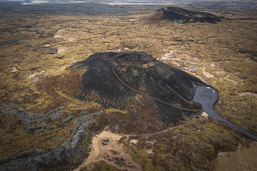 Aerial view of Saxhóll crater with the stair path, parking area, and surrounding lava field.