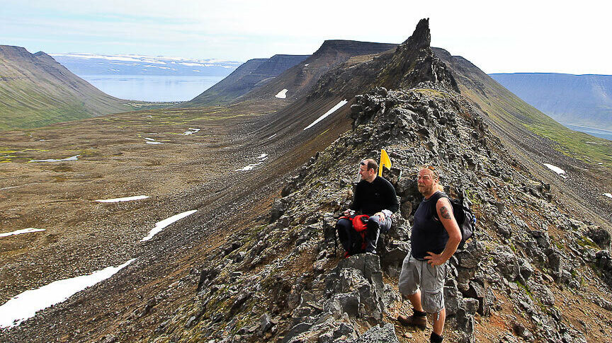 Hikers on a rocky ridge above Seljalandsdalur with fjord and mountain views in the Westfjords.