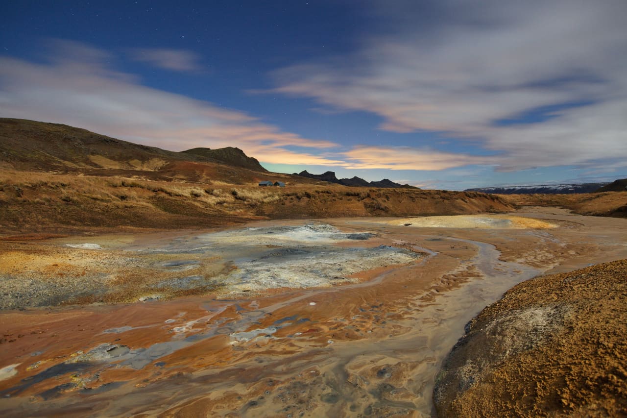 Colored geothermal mud and mineral ground at Seltún under evening light.
