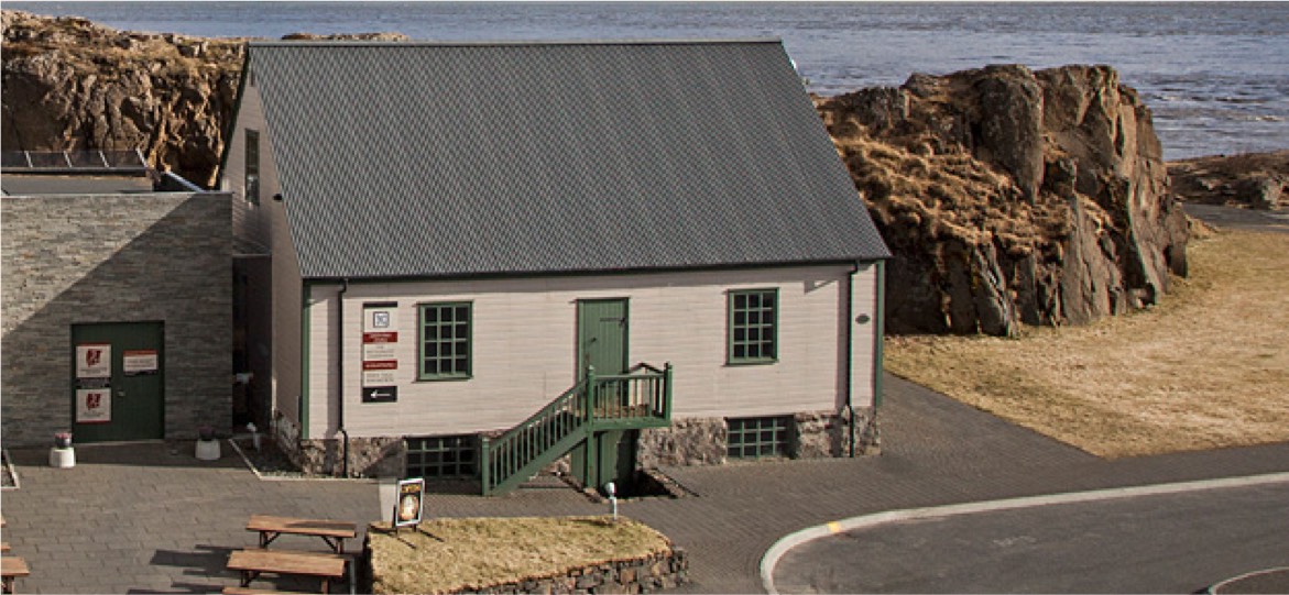 Historic Settlement Center buildings in Borgarnes with pale walls and green trim.