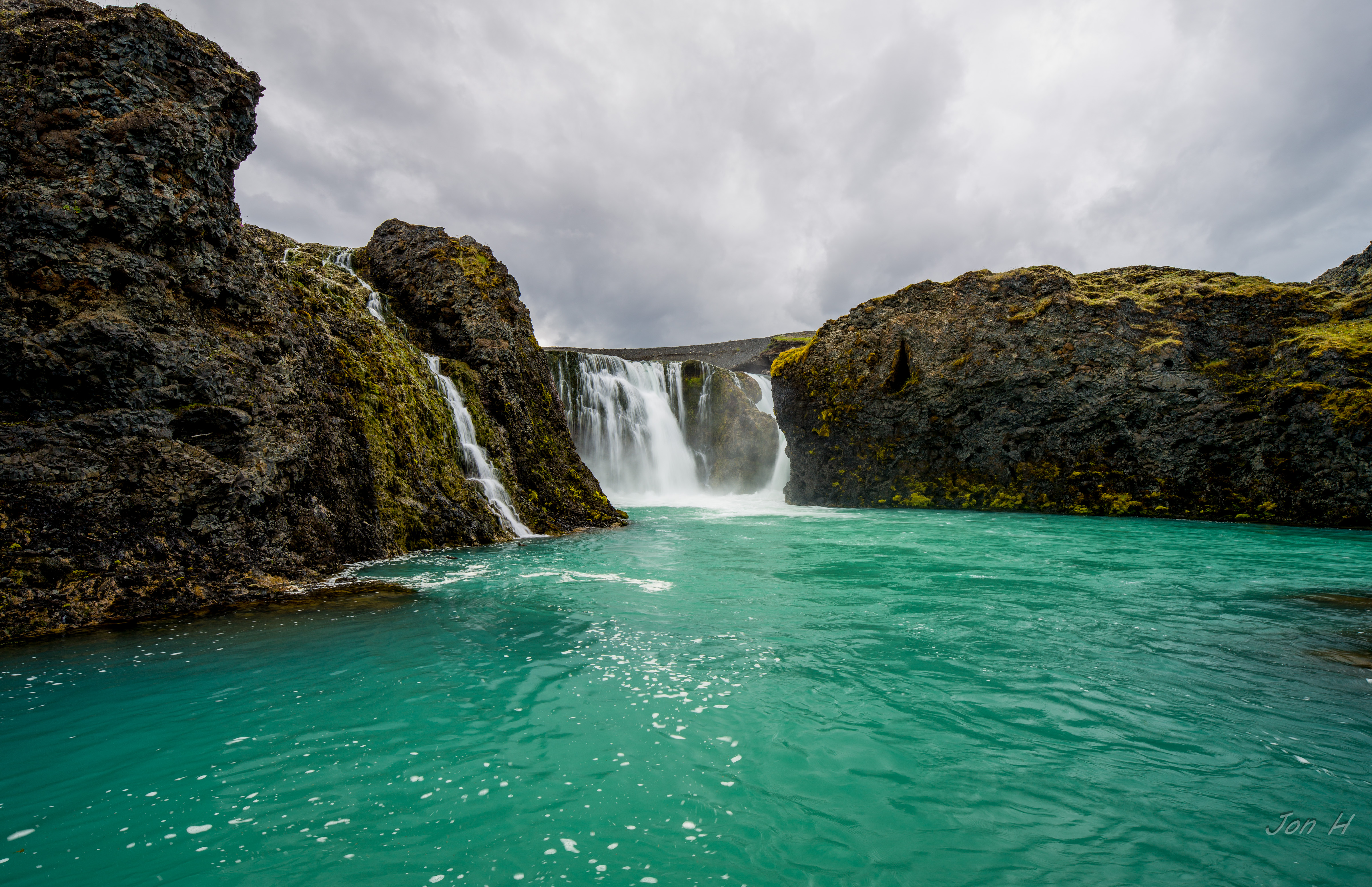 Sigöldufoss waterfall spreading across dark rock into a bright blue pool in the Icelandic Highlands.