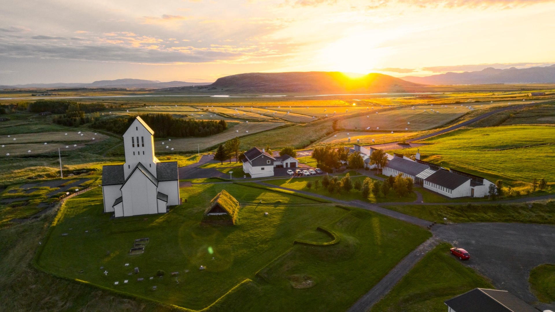 Skálholt Cathedral and the surrounding South Iceland fields seen from above at sunset.