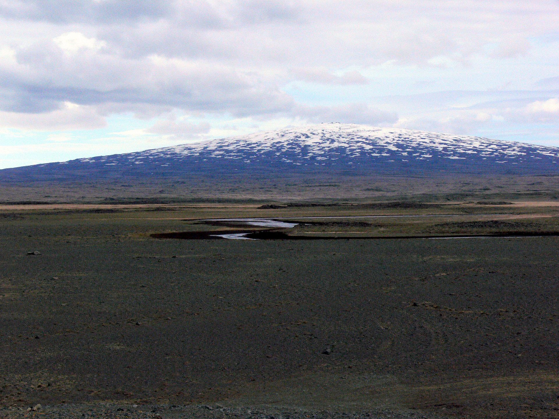 Skjaldbreiður rising beyond pale lava flats, dark lava ridges, and small pools on the highland edge north of Þingvellir.