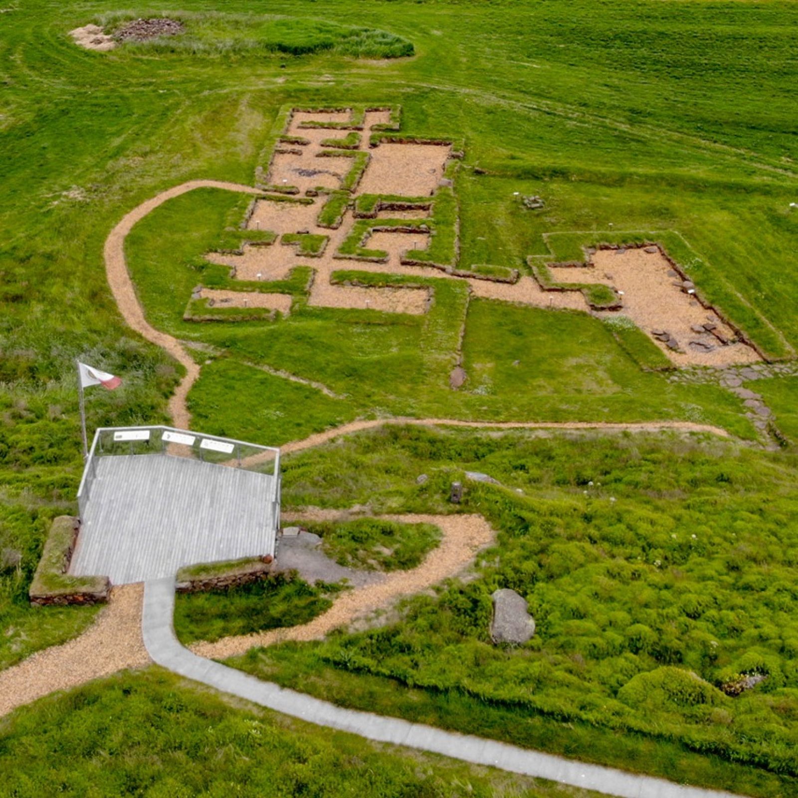Marked paths and low reconstructed walls outlining the medieval monastery ruins at Skriðuklaustur.